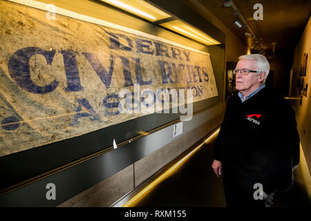 John Kelly, deren 17 Jahre alten Bruder, Michael, während der blutige Sonntag getötet wurde, steht neben der Derry Civil Rights Association Banner im Museum von Free Derry, dass an dem Tag, als blutiger Sonntag bekannt ist, durchgeführt wurde. Die Staatsanwaltschaft wird erwartet, zu verkünden, ob es Ermittlungen gegen Soldaten über den Tod von 13 Menschen in Londonderry am 30. Januar 1972 fortzusetzen. Stockfoto