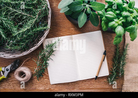 Frische Kräuter und leere Notepad auf hölzernen Tisch Stockfoto