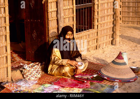 Arabische Folklore und Geschichte mit einem Emiratischen Bedouin Dame demonstriert das Korbflechten während des Dubai Handel Festival in den Vereinigten Arabischen Emiraten Stockfoto