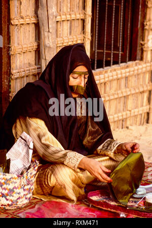 Arabische Folklore und Geschichte mit einem Emiratischen Bedouin Dame demonstriert das Korbflechten während des Dubai Handel Festival in den Vereinigten Arabischen Emiraten Stockfoto