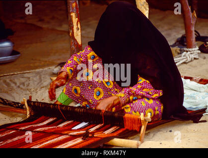 Arabische Folklore und Geschichte mit Emiratische Beduinenfrauen demonstrieren die Kunst des Webens Kamele und Ziegen Haar in Tradition Teppiche und Matten für den Einsatz um Ihre Desert Camp während des Dubai Handel Festival in den Vereinigten Arabischen Emiraten Stockfoto