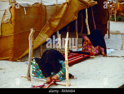 Arabische Folklore und Geschichte mit Emiratische Beduinenfrauen demonstrieren die Kunst des Webens Kamele und Ziegen Haar in Tradition Teppiche und Matten für den Einsatz um Ihre Desert Camp während des Dubai Handel Festival in den Vereinigten Arabischen Emiraten Stockfoto