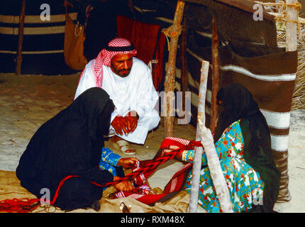 Arabische Folklore und Geschichte mit Emiratische Beduinenfrauen demonstrieren die Kunst des Webens Kamele und Ziegen Haar in Tradition Teppiche und Matten für den Einsatz um Ihre Desert Camp während des Dubai Handel Festival in den Vereinigten Arabischen Emiraten Stockfoto