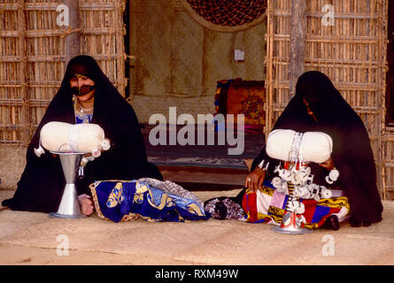 Arabische Folklore und Geschichte mit Emiratische Beduinenfrauen demonstrieren die Kunst des Webens silber Braid während des Dubai Handel Festival in den Vereinigten Arabischen Emiraten Stockfoto