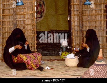 Arabische Folklore und Geschichte mit Emiratische Beduinenfrauen demonstrieren die Kunst des Webens silber Braid während des Dubai Handel Festival in den Vereinigten Arabischen Emiraten Stockfoto