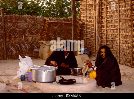 Arabische Folklore und Geschichte mit Emiratische Beduinenfrauen, die den alten Weg von Kochen über offenem Feuer - Backofen während des Dubai Handel Festival in den Vereinigten Arabischen Emiraten Stockfoto