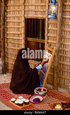 Arabische Folklore und Geschichte mit einem Emiratischen Bedouin Dame demonstriert Handarbeit während des Dubai Handel Festival in den Vereinigten Arabischen Emiraten Stockfoto