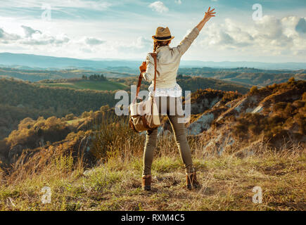 Von hinten Aktive reisende Frau in Wanderausrüstung mit Tasche im Sommer vor der Kulisse der Toskana, Italien Freude gesehen. Stockfoto