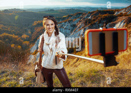 Lächelnd passen alleinreisender Frau in Wanderkleidung mit Tasche im Sommer Toskana Trail mit selfie Stick selfie. Stockfoto