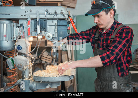 Die Zimmerleute mit elektrischen Bohrmaschine bohren Holzbrett Stockfoto