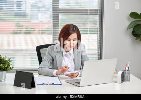 Asiatische Geschäftsfrau oder Buchhalter Arbeiten zeigen graph Diskussion und Analyse Daten Diagramme und Grafiken und mit einem Taschenrechner Zahlen zu berechnen. B Stockfoto