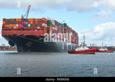 Drei Schlepper unterstützen das vollbeladene Ultra-Large UASC Containerschiff SAJIR beim Verlassen des Southampton Container Terminal, Hampshire, Großbritannien. Stockfoto