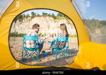 Leute, Sommer Tourismus und Natur Konzept - Junges Paar Tee trinken, in der Nähe von Zelt Stockfoto