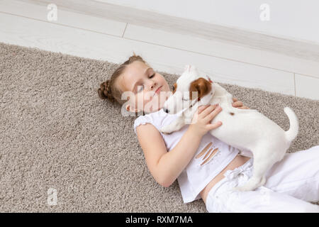 Haustier, Kindheit und Tier Konzept - Portrait von Kind Mädchen auf dem Boden liegend mit Welpen Jack Russell Terrier Stockfoto