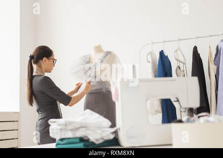 Schneiderin, Schneider, Mode und Showroom Konzept - Portrait von talentierten weiblichen Schneiderin arbeiten mit textilen zum Nähen von Kleidung Stockfoto