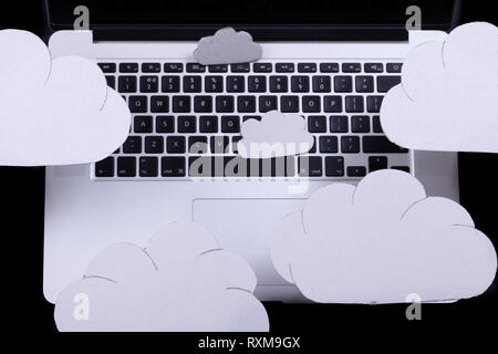 Cloud Computing Konzept mit Ausschnitt Wolken über einem Laptop Tastatur auf einem schwarzen Hintergrund Stockfoto