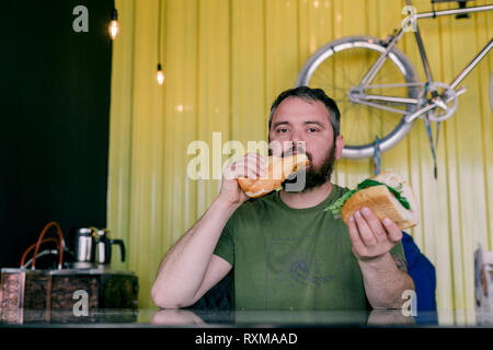 Der hungrige Mann, der ein Sandwich isst Stockfoto