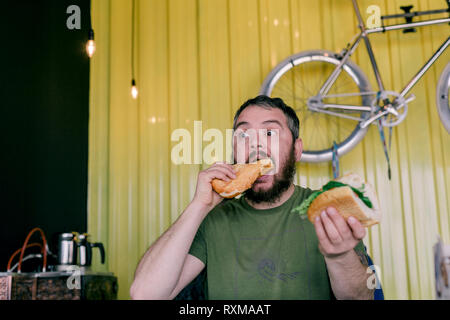 Der hungrige Mann, der ein Sandwich isst Stockfoto