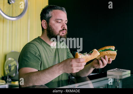 Der hungrige Mann, der ein Sandwich isst Stockfoto