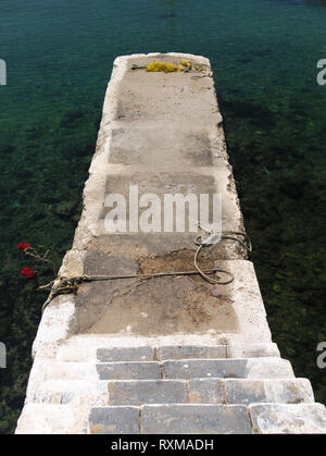 Treppe Pier mit einem Fischernetz auf kristallklarem Meer Wasser mit felsigen Boden zu zementieren. Stockfoto