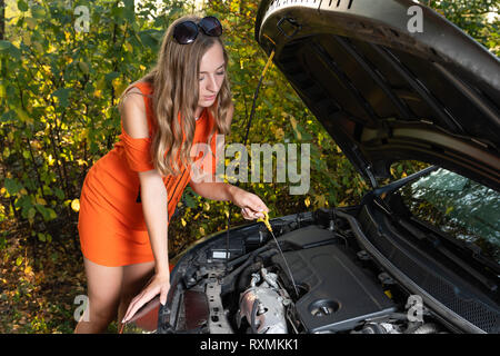 Auto Probleme. Die Frau prüft den Motorölstand. Stockfoto