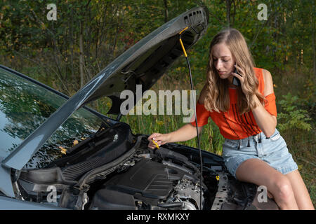 Junge Frau in der Nähe von Broken Auto sprechen per Telefon Unterstützung benötigt - Bild Stockfoto