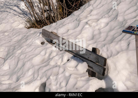Verschneite Holzbank unter einer Menge Schnee Winter Landschaft Stockfoto