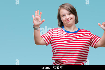 Junge erwachsene Frau mit Down-syndrom über isolierte Hintergrund angezeigt und zeigen mit den Fingern Nummer sechs, während lächelte zuversichtlich und fröhlich. Stockfoto