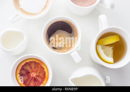 Kaffee, Cappuccino, Kakao und Tee auf einem weißen Tisch in minimalistisch-Cups. Ansicht von oben, flach Stockfoto