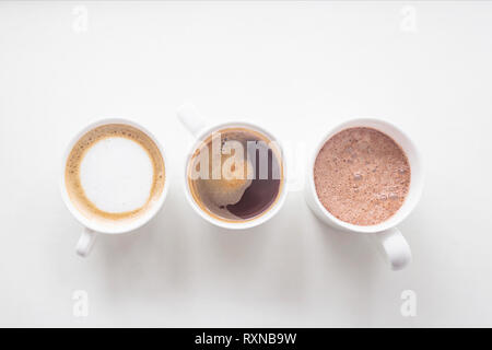 Kaffee, Cappuccino und Kakao in Weiß cups auf einem weißen Hintergrund. Drei Getränke. Ansicht von oben, flach Stockfoto