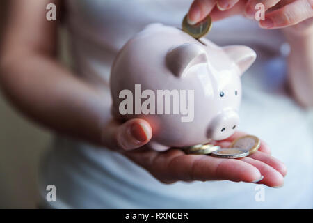 Weiblich frau Hände halten Pink piggy Bank und Geld Euro Münze. Speichern Investitionsbudget business Reichtum Rente Finanzen Geld Banken- Konzept Stockfoto