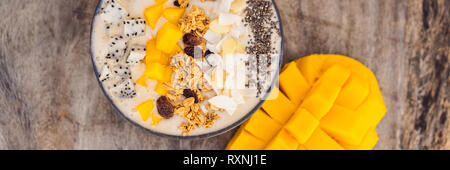 Smoothie Schüsseln mit Mango, Banane, Granola, Kokosraspeln, Dragon Obst, Chia Samen und Minze auf Holz- Hintergrund. Konzept Obst, Vitamine Stockfoto