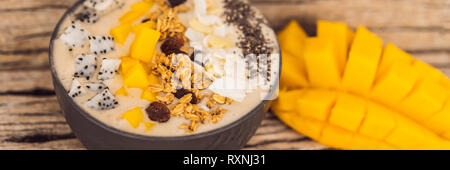 Smoothie Schüsseln mit Mango, Banane, Granola, Kokosraspeln, Dragon Obst, Chia Samen und Minze auf Holz- Hintergrund. Konzept Obst, Vitamine Stockfoto