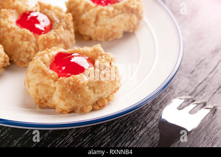 Cookies von Haselnuss Strawberry Shortcake mit Stau auf einer weißen Platte mit einem gemusterten Dessert Gabel auf dunklem Hintergrund, ganz in der Nähe. Die anhand von quantitativen Simulatio Stockfoto