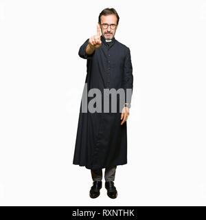 Mittleres Alter Mann, der katholische Priester gewand zeigte mit dem Finger auf und verärgerten Ausdruck Stockfoto