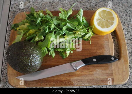 Büschel von grünen Garten Petersilie mit Zitrone und Avocado lag auf Küche Board zum Kochen Stockfoto