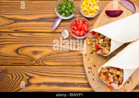 Burrito in tartilla mit Fleisch, Gemüse, weiße Bohnen, Paprika, Mais. Ein leckeres Mittagessen, mexikanische Küche, hausgemachte Snacks Stockfoto