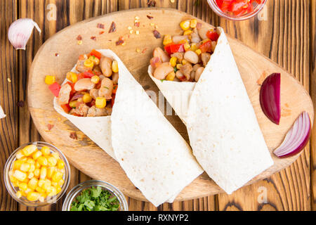 Burrito in tartilla mit Fleisch, Gemüse, weiße Bohnen, Paprika, Mais. Ein leckeres Mittagessen, mexikanische Küche, hausgemachte Snacks Stockfoto