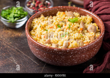 Bulgur mit der Türkei, Schwein oder Rind. Östlichen Reisgericht mit köstlichen Speisen. Geschmortes Fleisch mit Grütze. Pilav auf dunklem Hintergrund. Platz kopieren Stockfoto