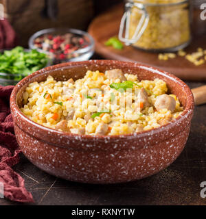 Bulgur mit der Türkei, Schwein oder Rind. Östlichen Reisgericht mit köstlichen Speisen. Geschmortes Fleisch mit Grütze. Pilav auf dunklem Hintergrund Stockfoto