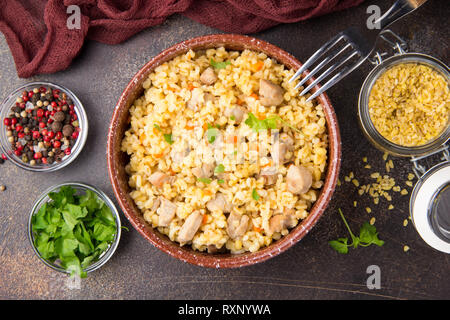 Bulgur mit der Türkei, Schwein oder Rind. Östlichen Reisgericht mit köstlichen Speisen. Geschmortes Fleisch mit Grütze. Pilav auf dunklem Hintergrund Stockfoto