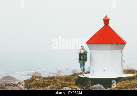 Reisende Frau in der Nähe von Leuchtturm genießen foggy Meerblick solo Reisen Lifestyle reise Abenteuer outdoor Einsamkeit Gefühle Stockfoto