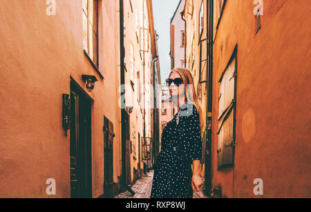 Blonde Frau wandern in Stockholm reisen allein Mode lifestyle Sommer Ferien in Schweden Altstadt Straße Stockfoto