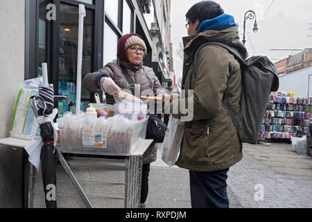 Eine lateinamerikanische Frau verkaufen obleas, einem Mexikanischen wafer Gebäck, bedeckt mit cajera, eine dicke süße Sirup. Auf der 82nd St. in Jackson Heights, Queens, New York City. Stockfoto