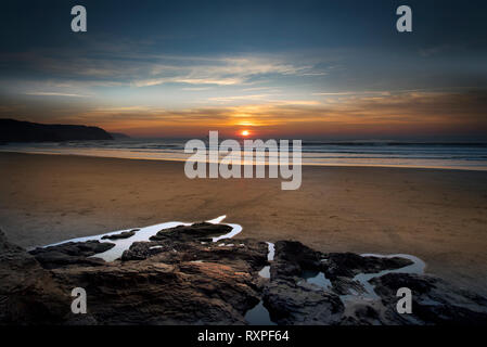 Schönen Sonnenuntergang über dem Rock Pools und weiten Sandstrand von perran Sands in Perranporth über cotty Punkt Cligga Kopf auf der North Cornwall Stockfoto