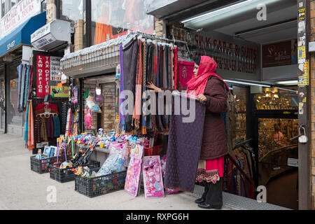 Ein Anbieter in ethnische Kleidung einstellen Schals für Verkauf an einen Außenpool stehen auf 74th Street in Jackson Heights, Queens, New York City. Stockfoto