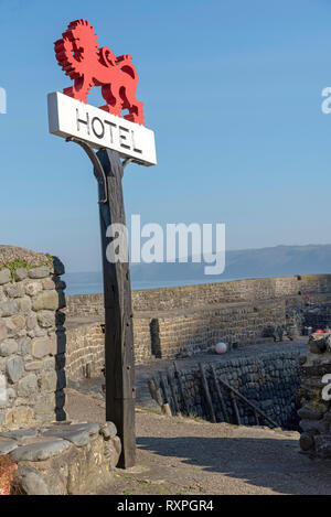 Clovelly, Devon, England, UK, März 2019. red Hotel Schild montiert auf einer alten Eiche post an der Küste in Clovelly. Stockfoto