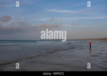 Dame im roten Mantel, die alleine stehen am Strand auf dem Sand mit in die Flut kommt Stockfoto