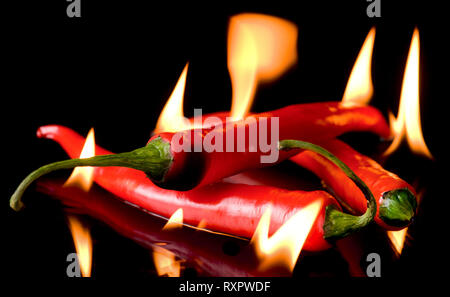 Sehr hot chili Pfeffer in Flammen und Ruß auf schwarzem Hintergrund Stockfoto