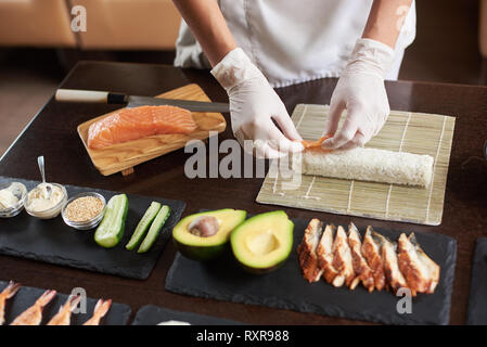 Close-up viev von Chef Hände Vorbereitung der japanischen Küche. Koch, Sushi Rollen im Restaurant mit vielen Zutaten auf den schwarzen Stein Platten. Stockfoto
